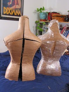 two wooden mannequins sitting on top of a bed next to each other