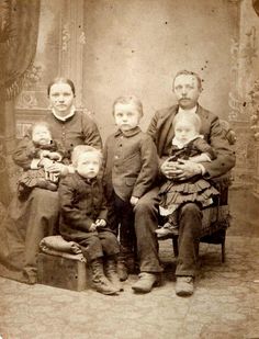 an old time photo of a family posing for a picture with two children and one adult