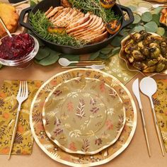 a table set for thanksgiving dinner with turkey, cranberry sauce and other foods