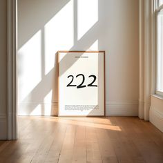 a white framed poster with the number twenty two on it in an empty room next to a window