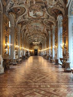 an ornately decorated hall with statues and chandeliers on either side of it