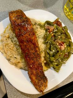 a white plate topped with meat, mashed potatoes and green beans