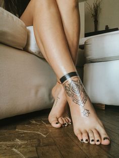 a woman's foot with tattoos on it sitting on the floor next to a bed