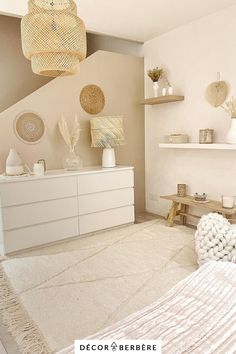 a bedroom with white furniture and neutral colors on the walls, along with hanging lights