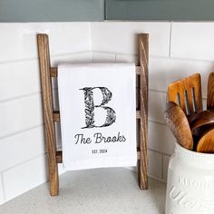 a kitchen towel with the letter b on it sitting next to wooden utensils