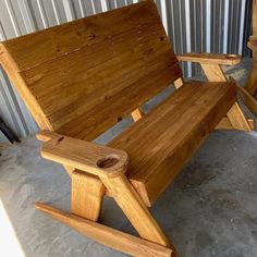 two wooden chairs sitting next to each other on cement floored area with corrugated wall in background