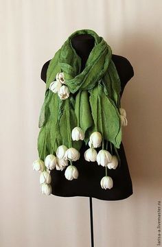 a green scarf with white flowers hanging on a mannequin's dummy stand