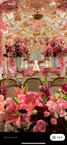 a room filled with lots of pink flowers and chandelier hanging from the ceiling