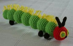 a crocheted caterpillar sitting on top of a white tablecloth covered floor