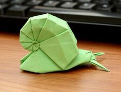 a green origami hat sitting on top of a wooden table next to a keyboard