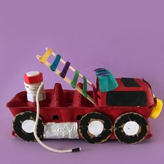 a toy firetruck made out of construction materials on a purple background with thread spools