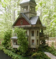 a small house in the middle of some bushes and trees with a clock tower on top