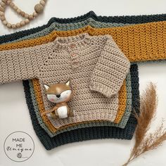 a crocheted sweater with a fox on it and a beaded necklace next to it