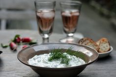 there is a bowl of cream and bread on the table with two glasses of wine