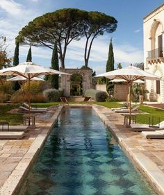 an outdoor swimming pool surrounded by lawn chairs and umbrellas