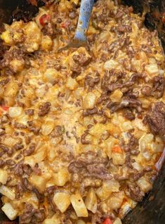 the food is being cooked in the crock pot with a blue spatula on top