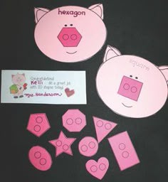 some pink paper cutouts and stickers on a black surface