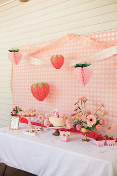 a table topped with cake and cupcakes next to a pink checkered wall