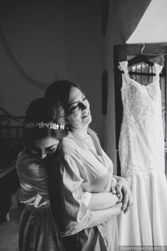 two women standing next to each other in front of a dress hanging on a rack