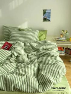 an unmade bed with green and white striped sheets