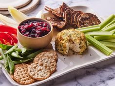 a white plate topped with food next to crackers and veggies