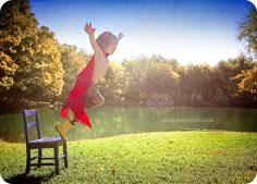 a young boy is jumping up into the air on a chair in front of a pond