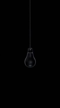 a black light bulb hanging from a chain on a dark background with no one in it