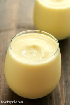 two glasses filled with yellow liquid sitting on top of a wooden table