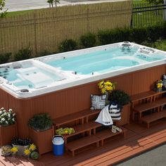 a large hot tub sitting on top of a wooden deck next to a garden area