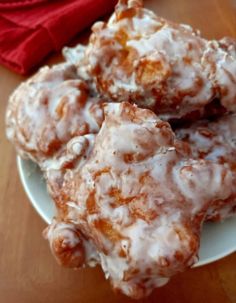 three glazed donuts on a white plate next to a red cloth and napkins