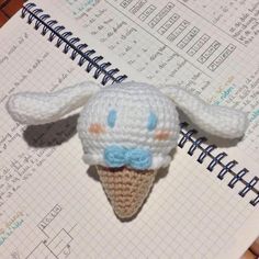 an ice cream cone with a crochet bunny head on top of it next to a spiral notebook