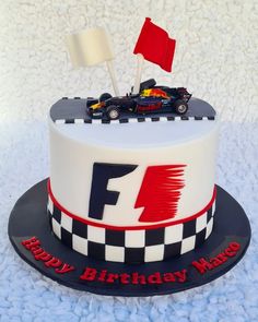 a birthday cake with a racing car on top and a red flag sticking out of it