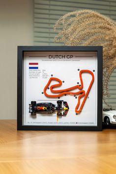 a framed photograph of a race track with a car in the middle and a plant next to it