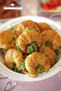 small croissants are arranged in a bowl on a table with other food items