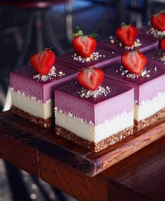 several desserts with strawberries are arranged on a wooden table, ready to be eaten