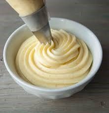 a white bowl filled with cream on top of a wooden table