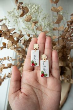 someone is holding two small earrings with strawberries on them