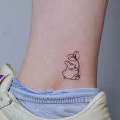 a small tattoo on the ankle of a woman's foot, depicting a rabbit holding a flower