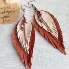 two pairs of brown and white feather earrings with beaded details on the end of each ear