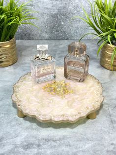 two perfume bottles sitting on top of a tray next to some potted planters