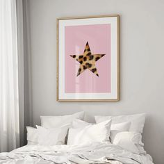 a bed with white linens and a framed star print on the wall above it