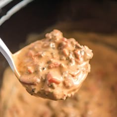 a spoon full of food that is being lifted from the slow cooker to be cooked