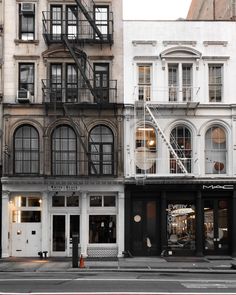 an empty street in front of tall buildings with fire escapes on the second floor and third story