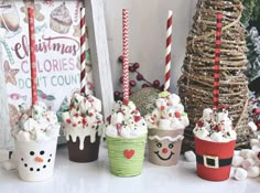 cupcakes decorated with frosting and candy are lined up on a table next to a christmas tree