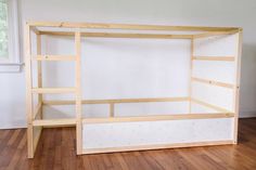 a wooden bed frame sitting on top of a hard wood floor next to a window