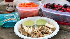 the meal is prepared and ready to be eaten on the picnic table with fruit, veggies, and chicken