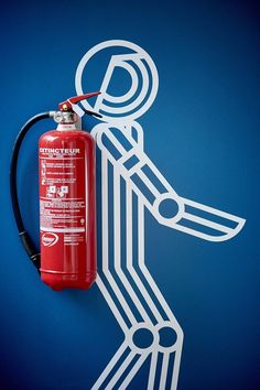 a red fire extinguisher attached to the side of a blue wall with white lines