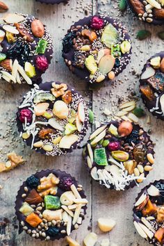 chocolate cupcakes topped with nuts, seeds and other toppings on a wooden table