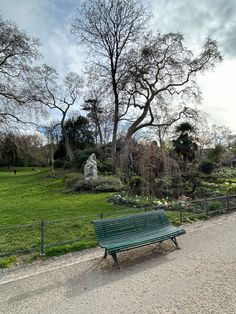 a green bench sitting on the side of a road next to a lush green park