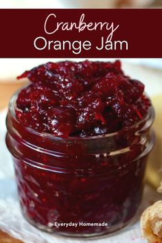 cranberry orange jam in a glass jar on a white napkin next to some bread